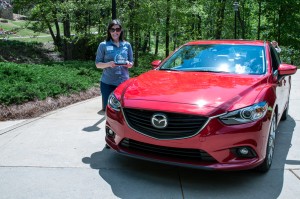 Tamara Mlynarczyk, Manager, Public Affairs, Mazda North American Operations holds GAAMA's Technology Choice Award alongide the winning 2015 Mazda 6.